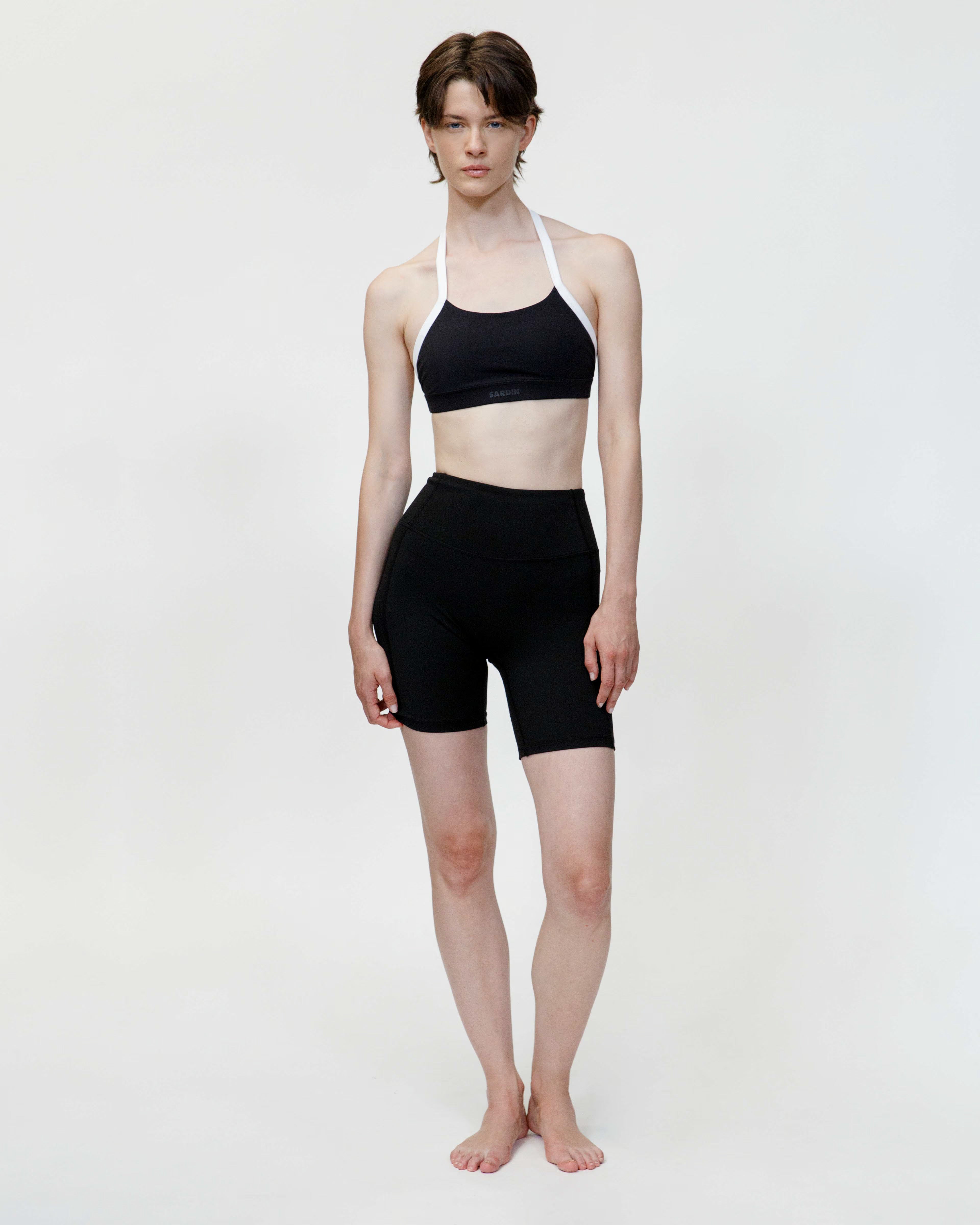 Person wearing a black sports bra and shorts on a white background