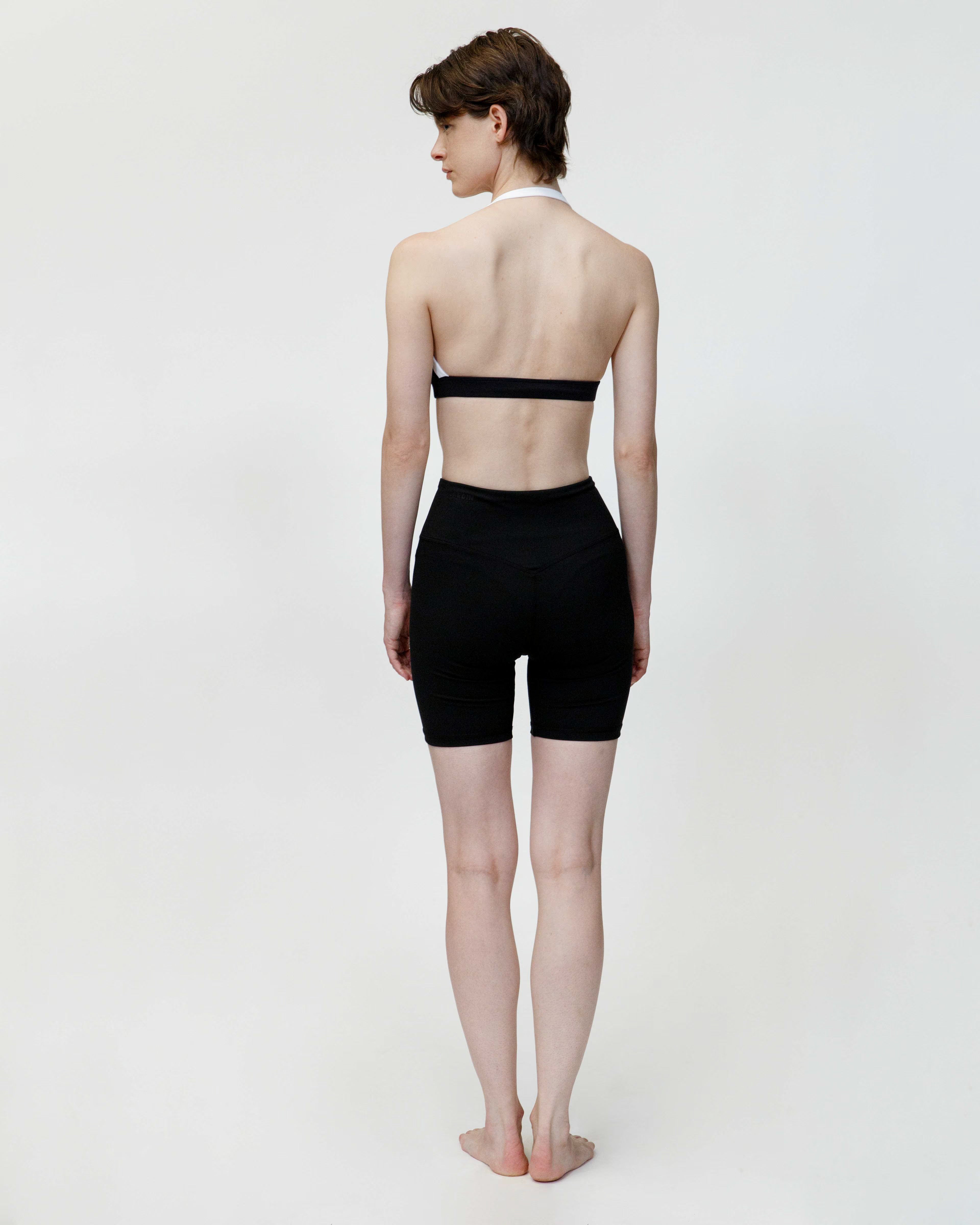 Person wearing a black strapless top and black high-waisted shorts on a white background