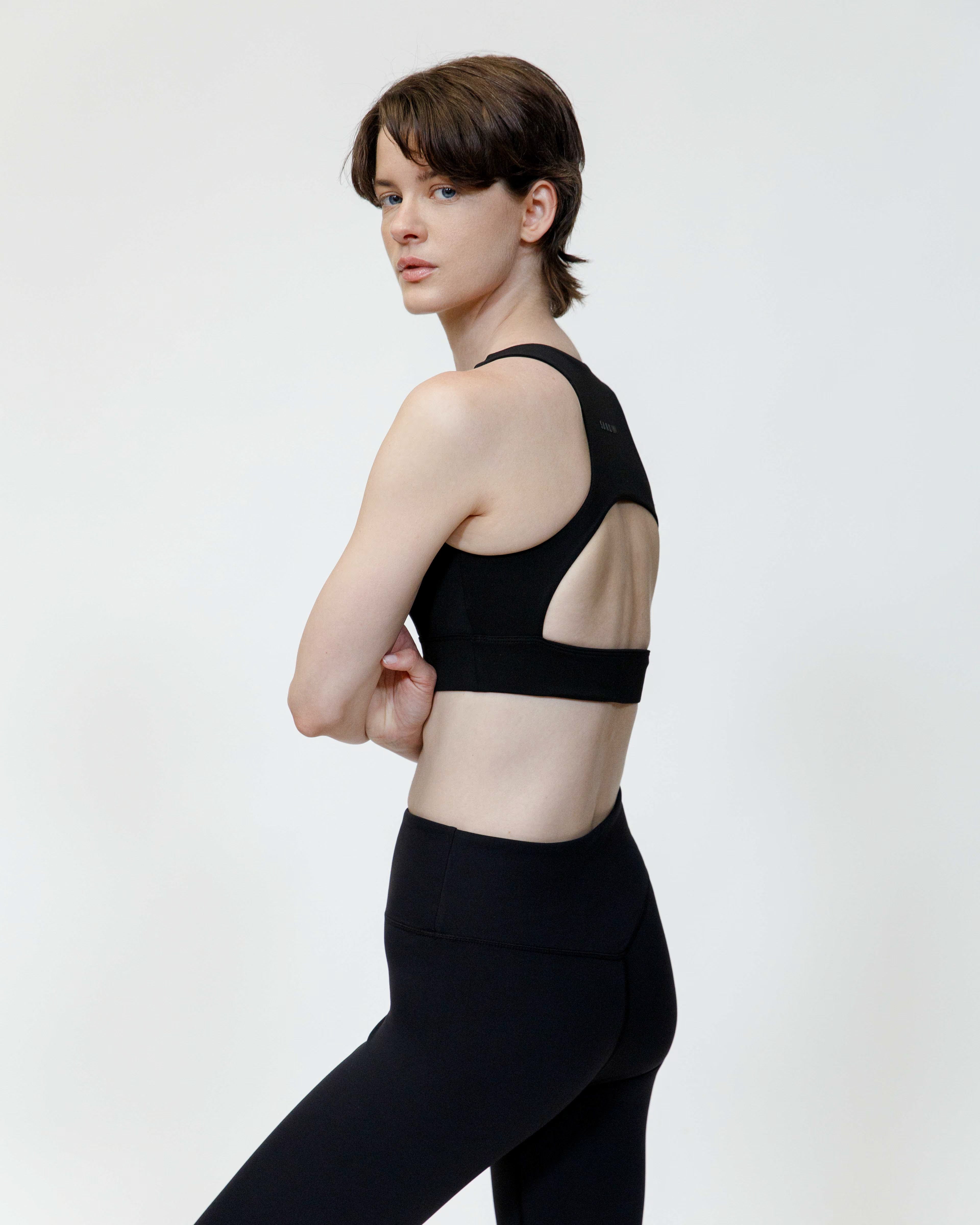 Woman wearing a black sports bra and leggings on a white background