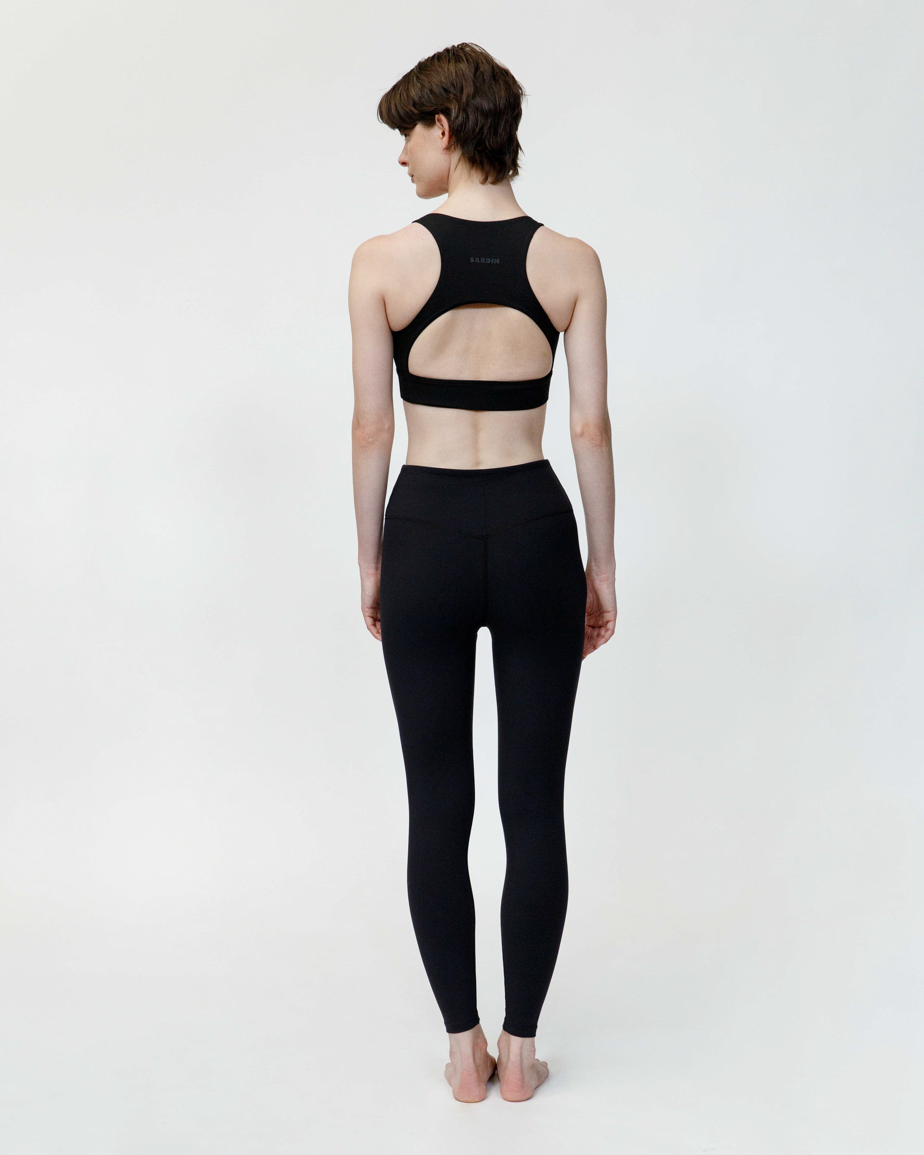 Person wearing a black sports bra and leggings on a white background