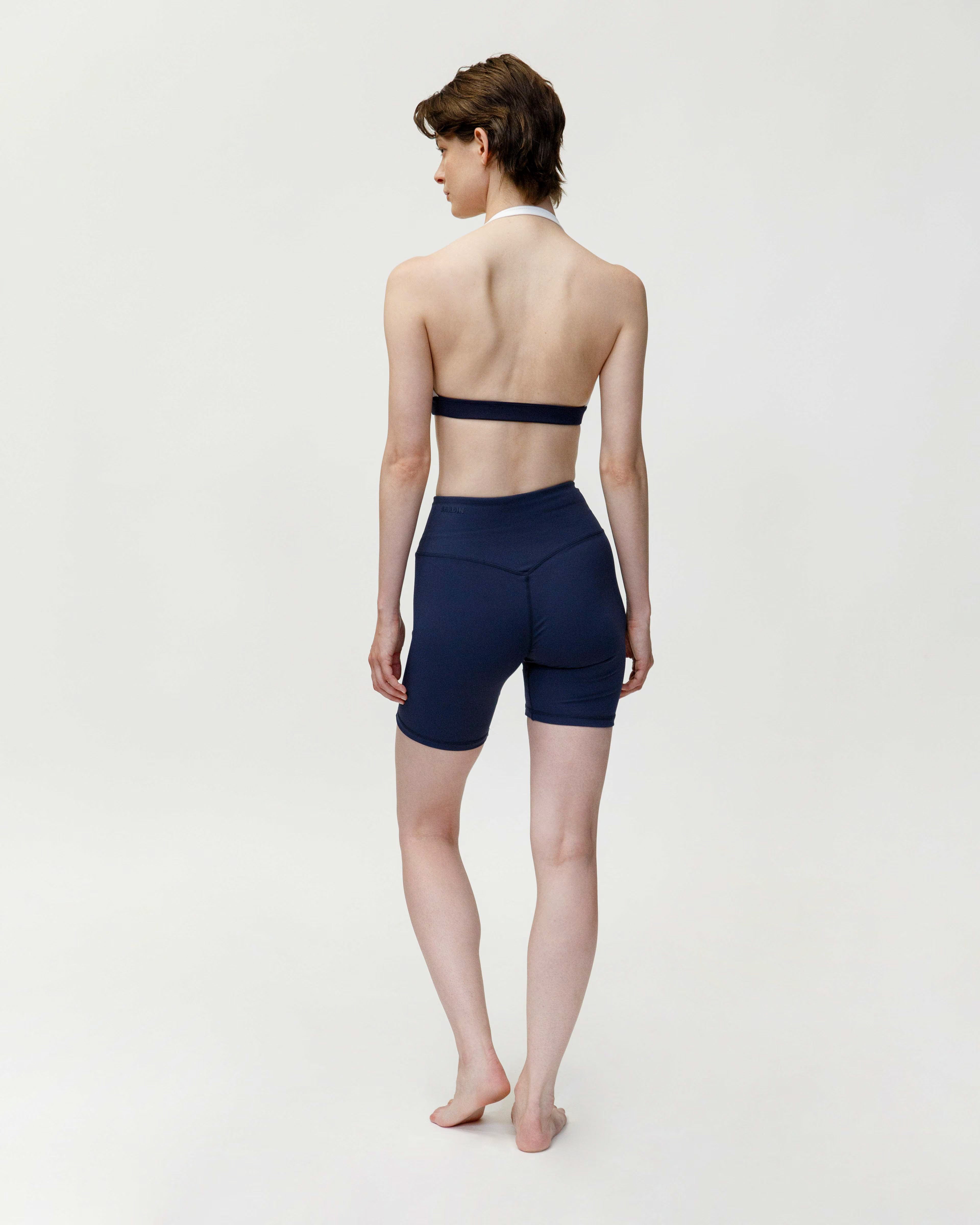 Person wearing a navy blue strapless top and shorts on a white background