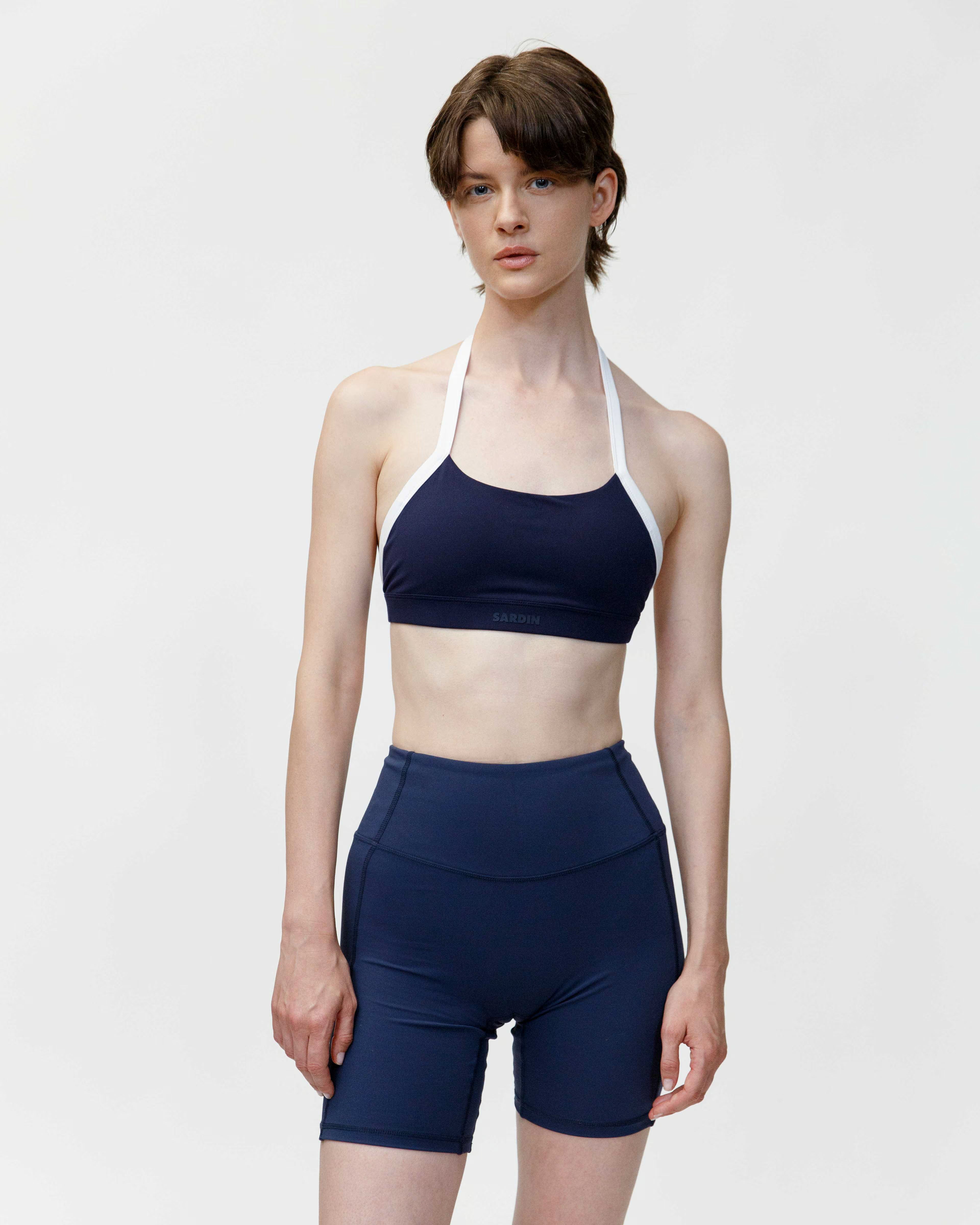 Person wearing a navy sports bra and shorts set on a white background